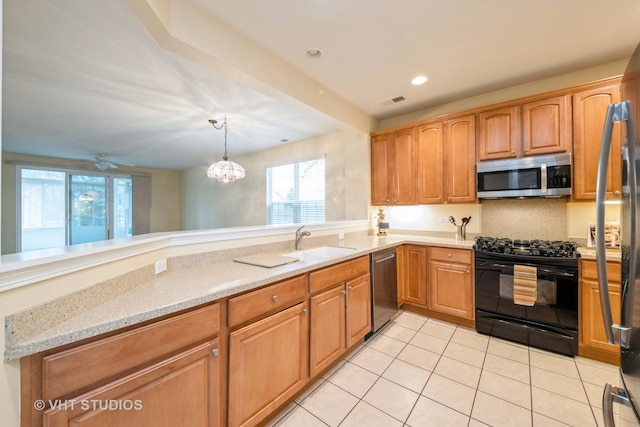 kitchen featuring decorative light fixtures, light stone counters, light tile patterned floors, appliances with stainless steel finishes, and a sink