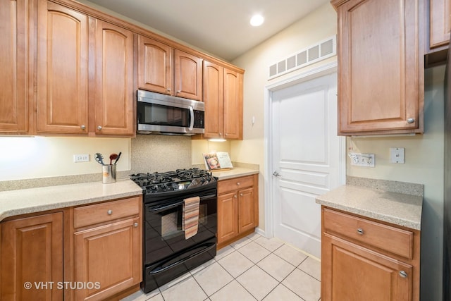 kitchen with visible vents, stainless steel microwave, recessed lighting, light tile patterned flooring, and black range with gas cooktop