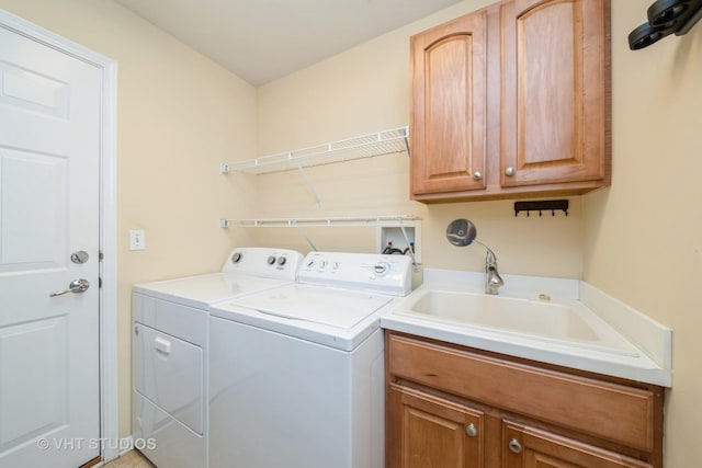 washroom with cabinet space, washing machine and dryer, and a sink