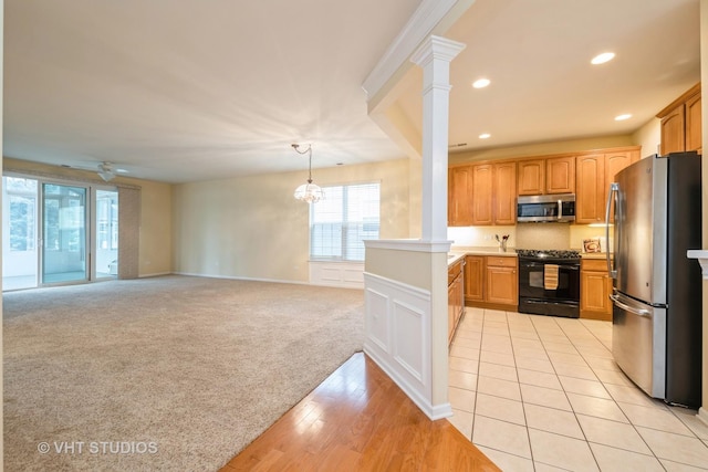 kitchen with ornate columns, recessed lighting, appliances with stainless steel finishes, ceiling fan with notable chandelier, and light colored carpet