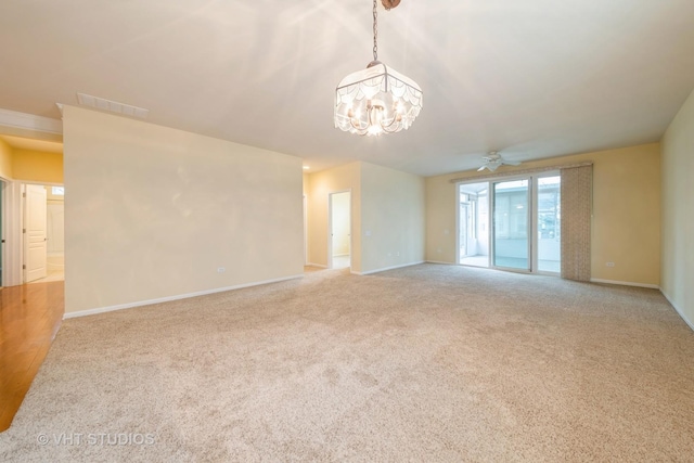 carpeted empty room with visible vents, ceiling fan with notable chandelier, and baseboards