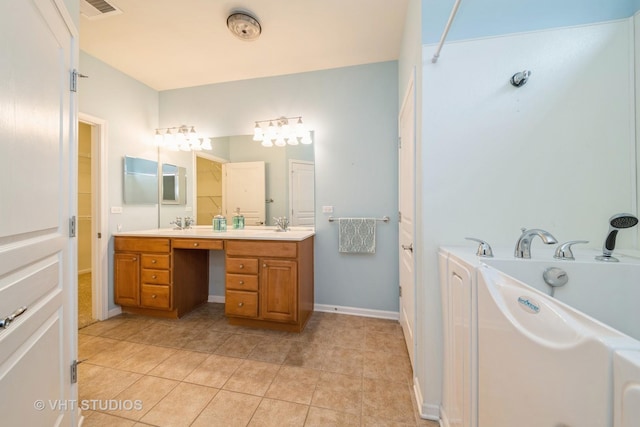 bathroom with a garden tub, double vanity, washer / dryer, tile patterned floors, and a sink