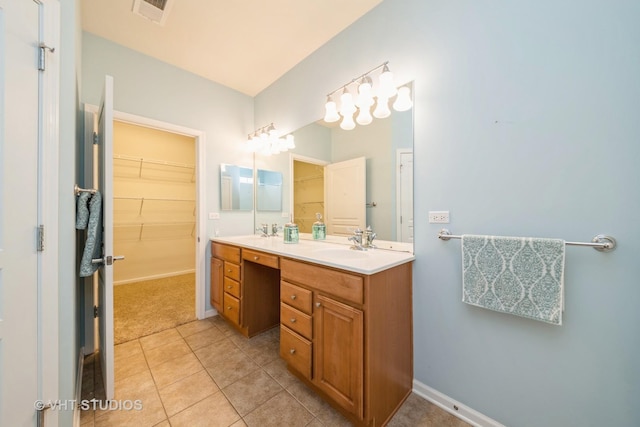 full bath with a sink, double vanity, a spacious closet, and tile patterned flooring