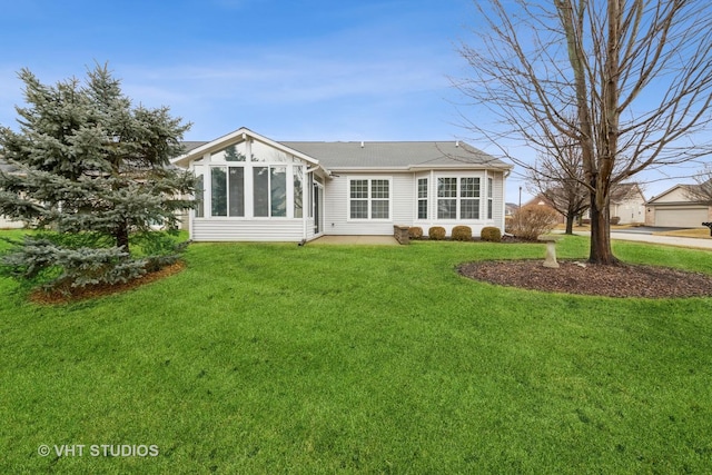 back of property with a yard and a sunroom