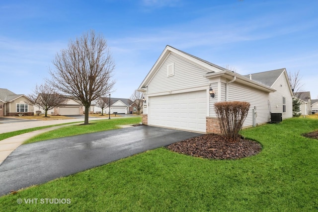 view of side of home featuring brick siding, a residential view, a lawn, a garage, and driveway