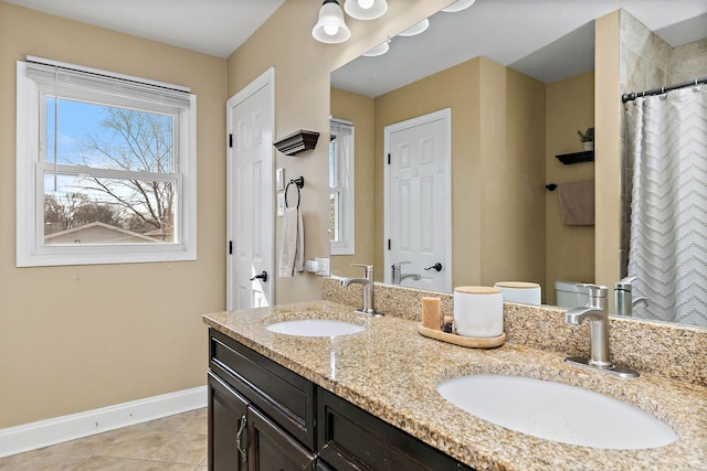 bathroom featuring tile patterned floors, double vanity, baseboards, and a sink