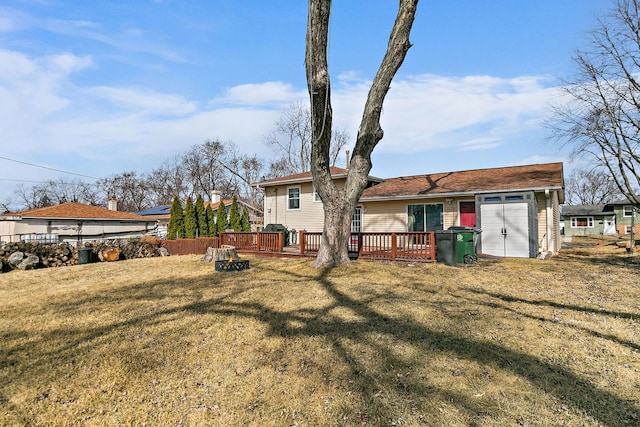 rear view of house featuring a lawn, an attached garage, a deck, and fence