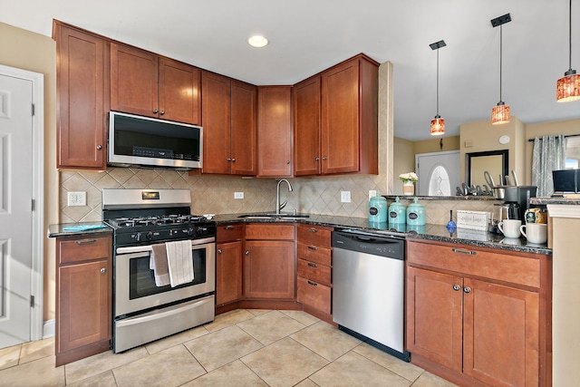 kitchen featuring decorative backsplash, dark stone countertops, brown cabinetry, stainless steel appliances, and a sink