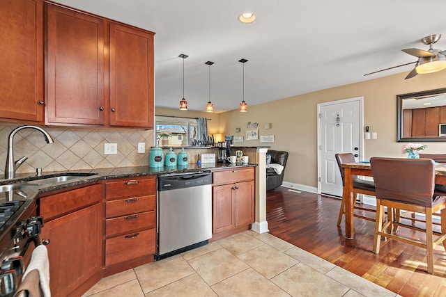 kitchen featuring a ceiling fan, a peninsula, a sink, decorative backsplash, and stainless steel appliances