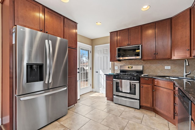 kitchen with a sink, decorative backsplash, light tile patterned floors, and stainless steel appliances