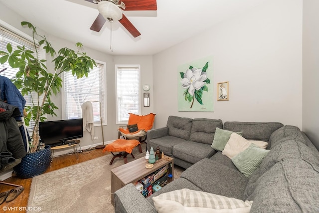 living room featuring ceiling fan, baseboards, and wood finished floors