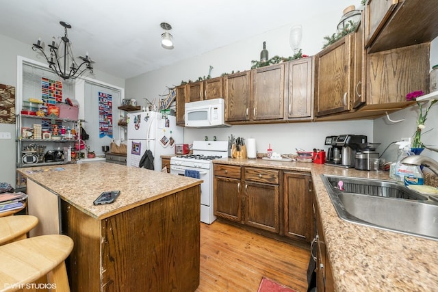 kitchen with a center island, light countertops, light wood-style floors, a sink, and white appliances