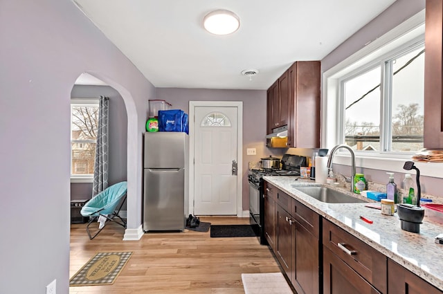 kitchen with visible vents, light wood-style flooring, freestanding refrigerator, black range with gas cooktop, and a sink