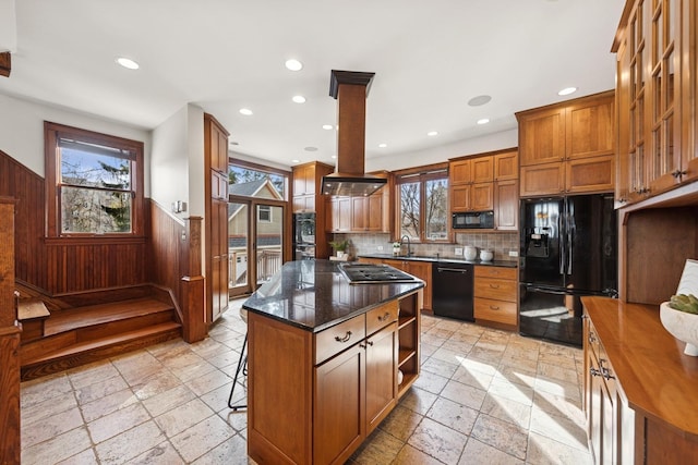 kitchen featuring stone tile floors, a wainscoted wall, open shelves, brown cabinets, and black appliances