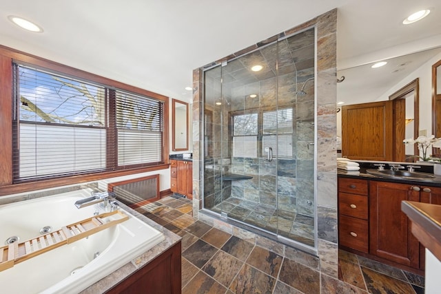 bathroom with a stall shower, a tub with jets, stone tile flooring, vanity, and recessed lighting