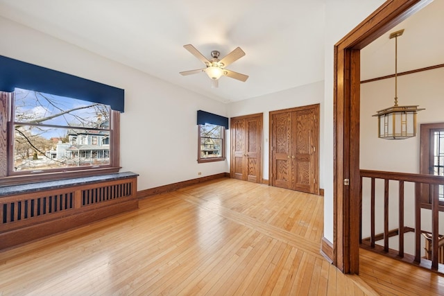 interior space featuring light wood finished floors, baseboards, and a ceiling fan