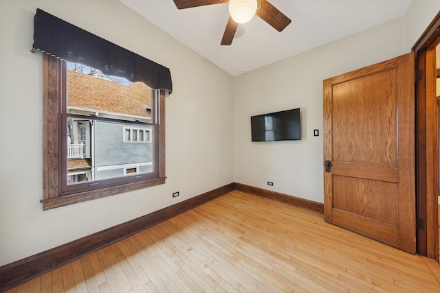 empty room featuring light wood-style flooring, baseboards, and a ceiling fan