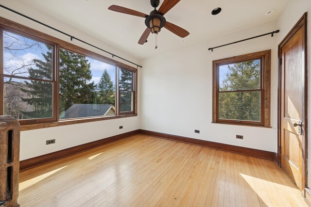 spare room with a ceiling fan, light wood-style flooring, and baseboards