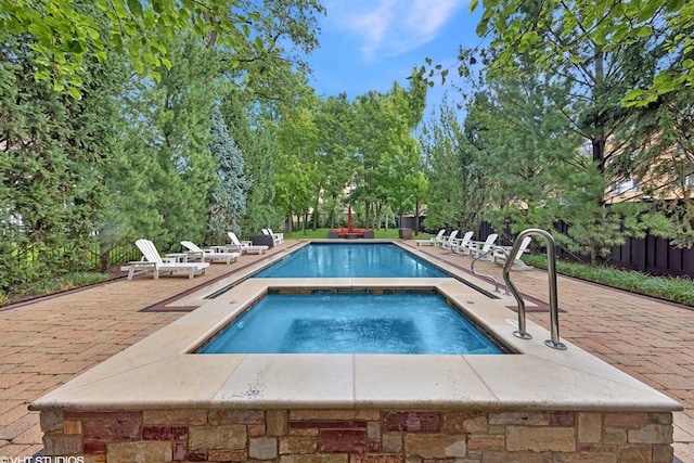 view of swimming pool with a patio area, fence, a fenced in pool, and an in ground hot tub