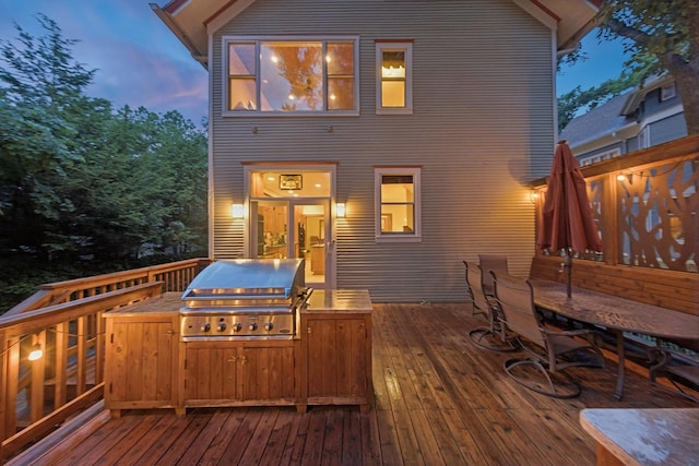 deck at dusk with an outdoor kitchen and grilling area