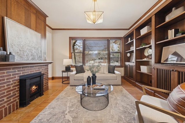 sitting room with baseboards, ornamental molding, a fireplace, and light wood-style floors