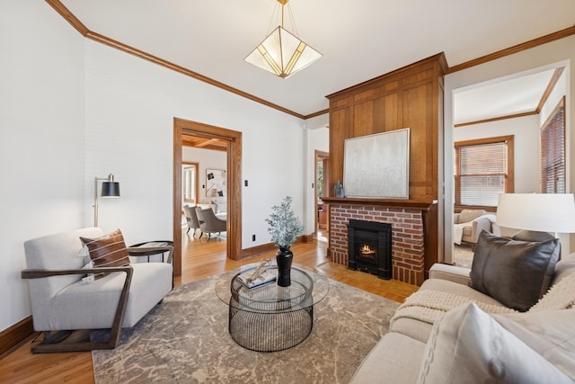 living area with a brick fireplace, crown molding, light wood-style flooring, and baseboards