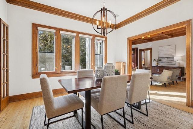 dining space featuring baseboards, crown molding, light wood-style flooring, and an inviting chandelier