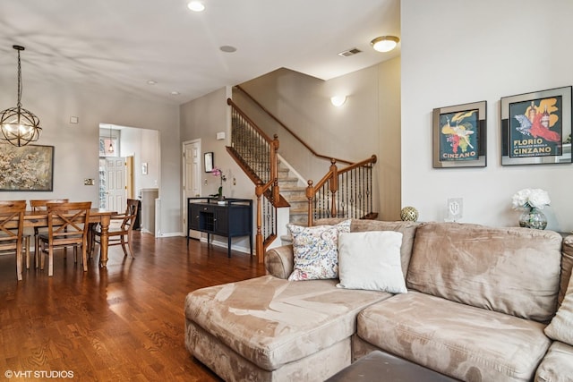 living area with baseboards, visible vents, wood finished floors, stairs, and a chandelier