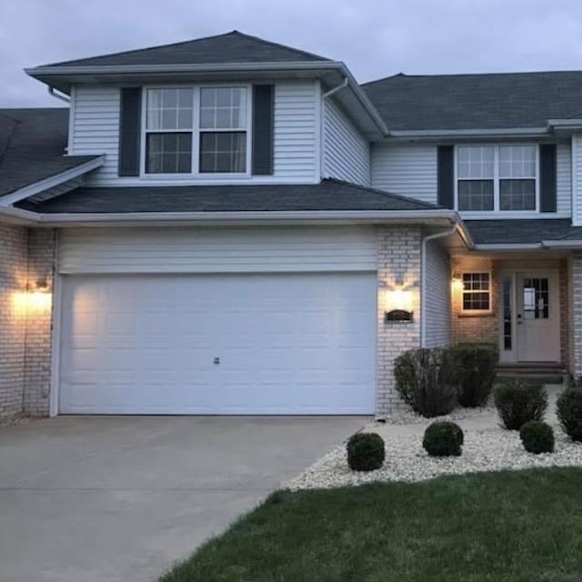 view of front of house with concrete driveway, brick siding, and an attached garage