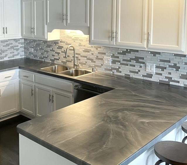 kitchen featuring decorative backsplash, dishwasher, a kitchen breakfast bar, white cabinetry, and a sink