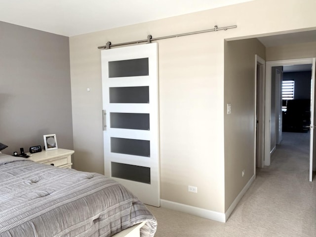 bedroom featuring baseboards, a barn door, and light colored carpet