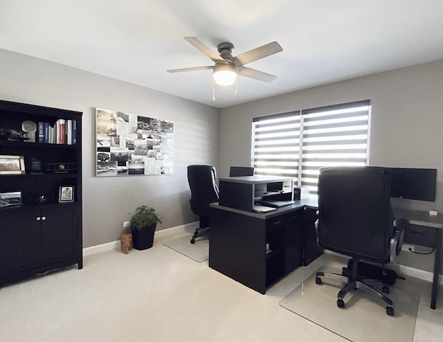 office space featuring baseboards, a ceiling fan, and light colored carpet