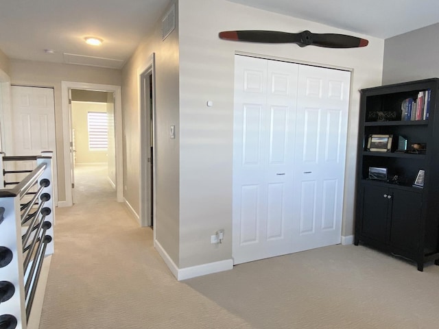 hall with light carpet, baseboards, and visible vents