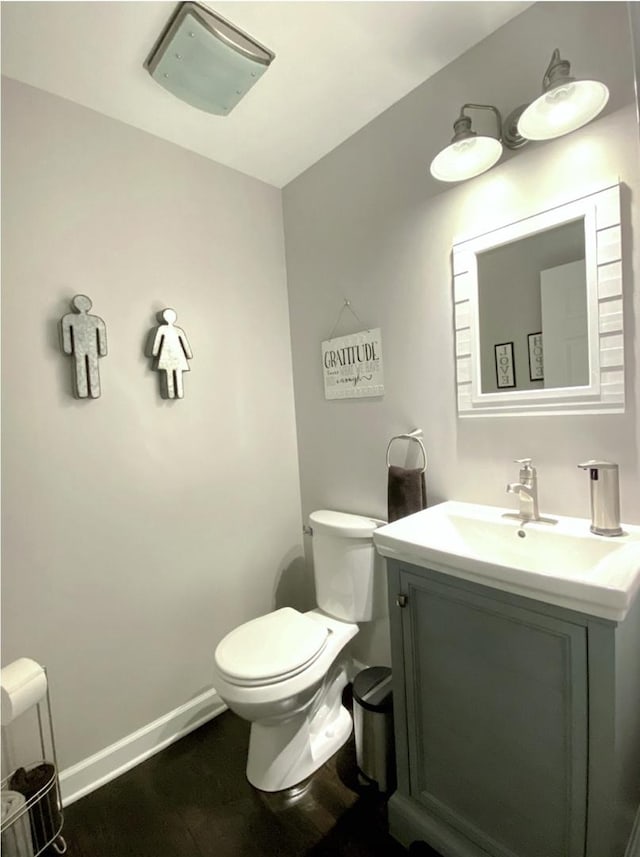 bathroom with wood finished floors, vanity, toilet, and baseboards