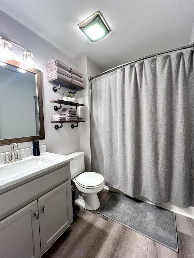 full bath with a shower with curtain, vanity, toilet, and wood finished floors