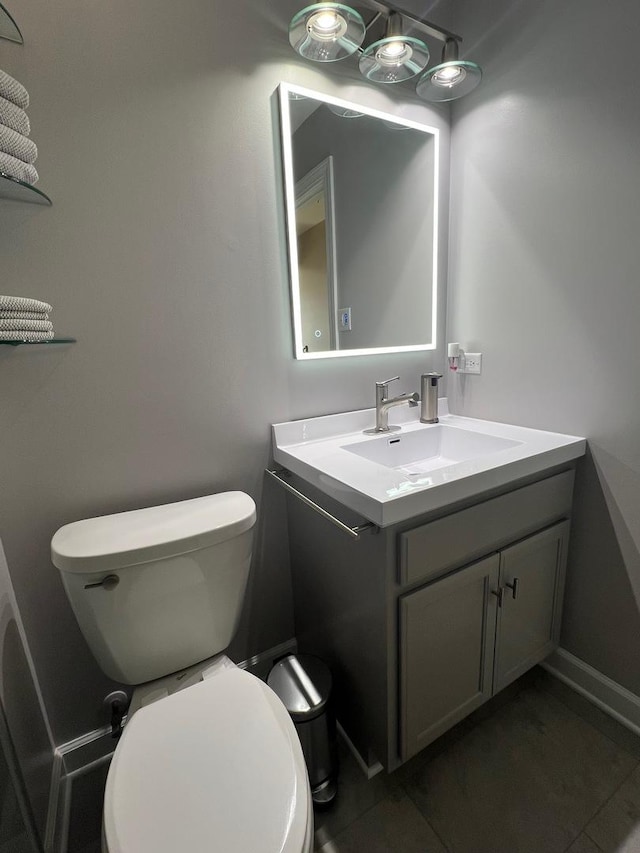 bathroom featuring baseboards, vanity, and toilet