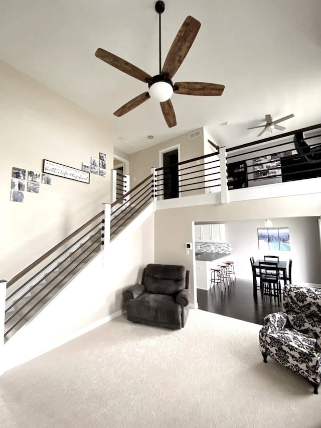 sitting room with visible vents, stairway, a high ceiling, a ceiling fan, and baseboards