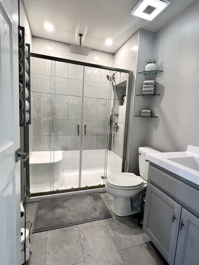 bathroom with a stall shower, vanity, and toilet