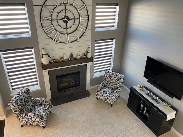 carpeted living area with a large fireplace and a high ceiling