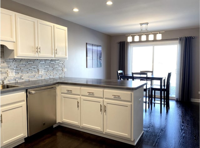 kitchen featuring tasteful backsplash, dishwasher, dark wood-type flooring, a peninsula, and white cabinetry