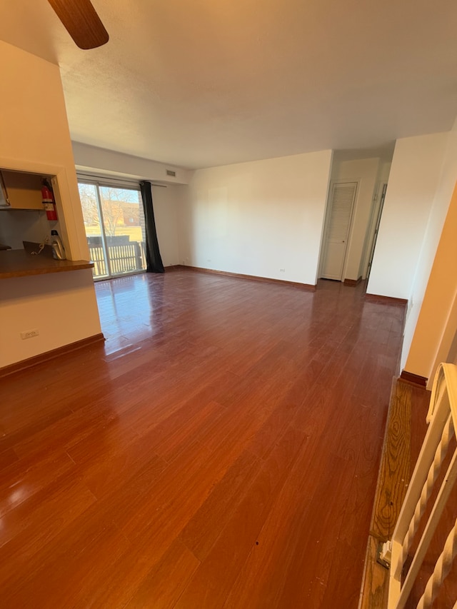 unfurnished living room featuring dark wood-style floors, visible vents, baseboards, and a ceiling fan