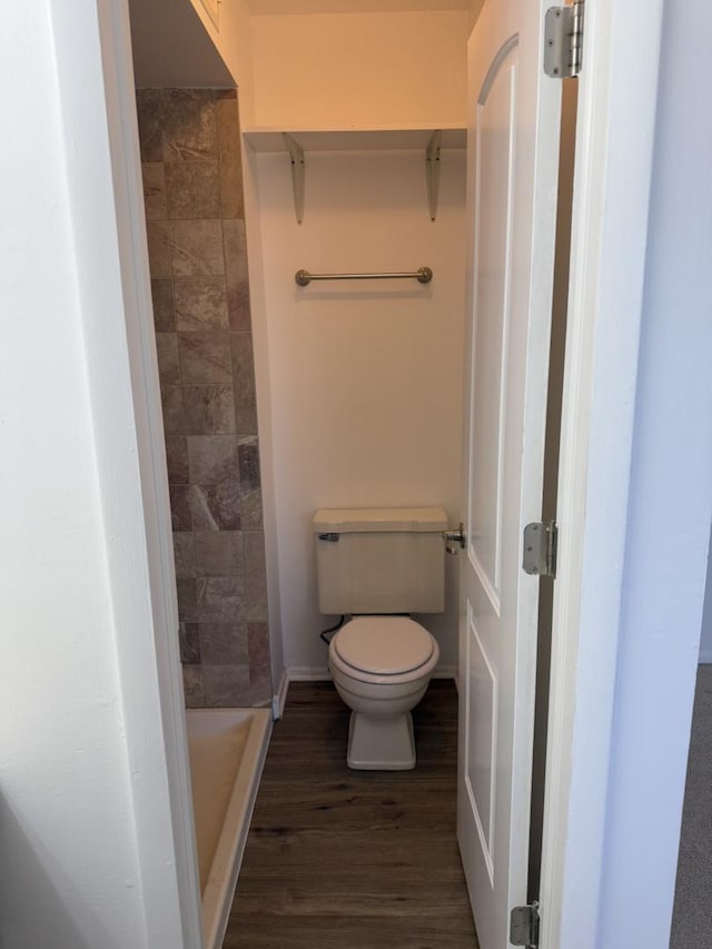 bathroom featuring toilet, a stall shower, and wood finished floors