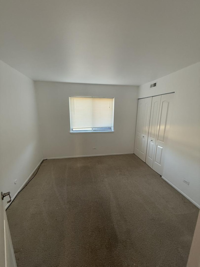 unfurnished bedroom with baseboards, carpet, visible vents, and a closet