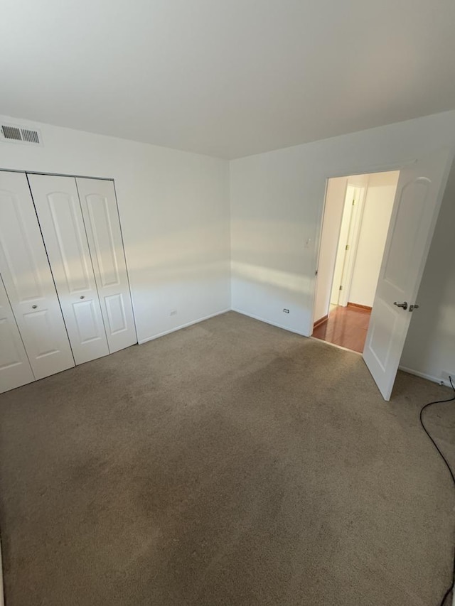 unfurnished bedroom with a closet, visible vents, and carpet flooring