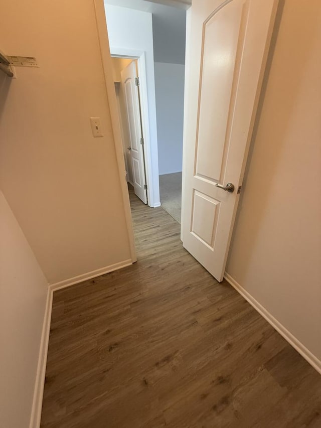 corridor featuring baseboards and dark wood-style flooring