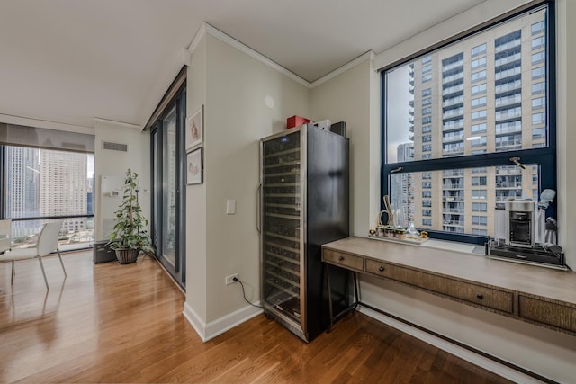 hallway featuring beverage cooler, ornamental molding, wood finished floors, and visible vents