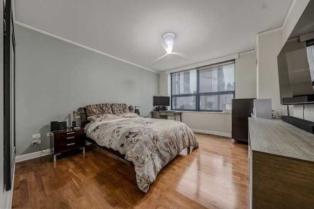 bedroom with ornamental molding, baseboards, and wood finished floors