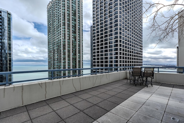 view of patio with a view of city, a water view, and a balcony