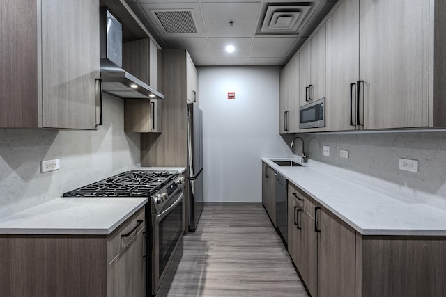 kitchen featuring stainless steel appliances, a sink, visible vents, decorative backsplash, and wall chimney exhaust hood