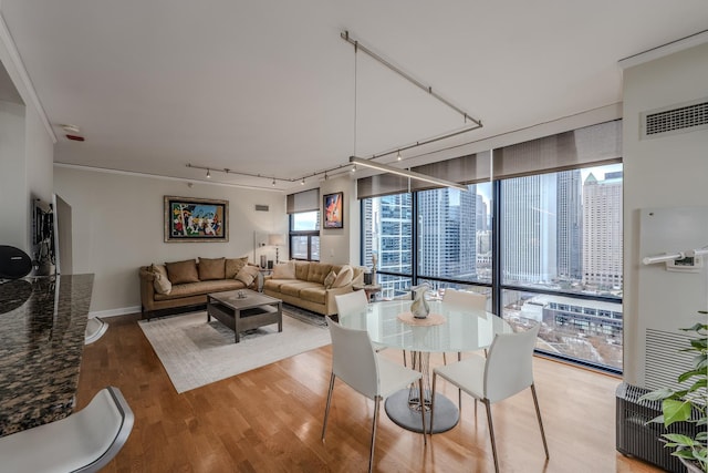 living area featuring visible vents, baseboards, light wood-type flooring, floor to ceiling windows, and a view of city